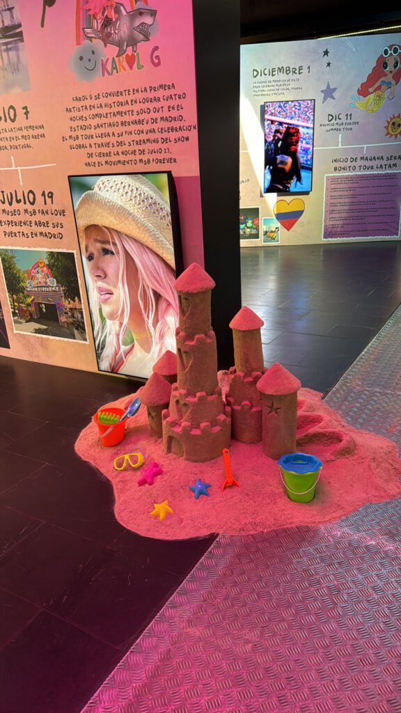 Castillo de arena rosa con juguetes infantiles en el museo Mañana Será Bonito de Karol G en Madrid, parte del diseño experiencial y decorativo del tour.