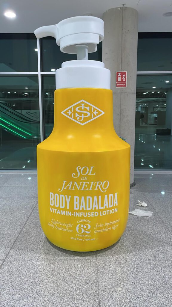 Botella gigante de Sol de Janeiro Body Badalada expuesta en el aeropuerto de Málaga como elemento de branding experiencial y retail impactante.